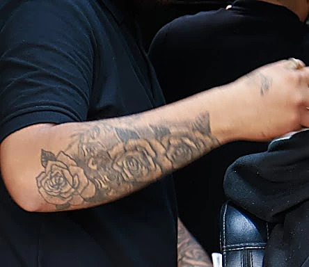 Antebrazo tatuado de un barbero trabajando con la máquina